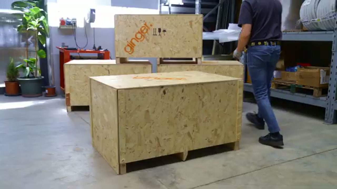 The original OSB shipping crate, branded with the Ginger logo, standing closed on a warehouse floor