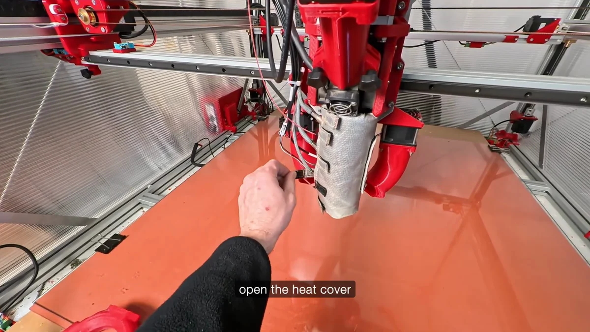 A hand releasing the clip on the barrel's insulating heat cover, the wrap opened away from the barrel